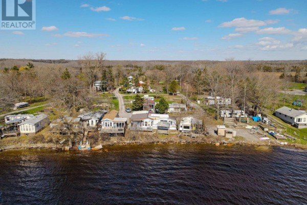 Waterfront aerial view of a property featuring multiple mobile homes and recreational vehicles by the water. - 181 Melville Road, Prince Edward County