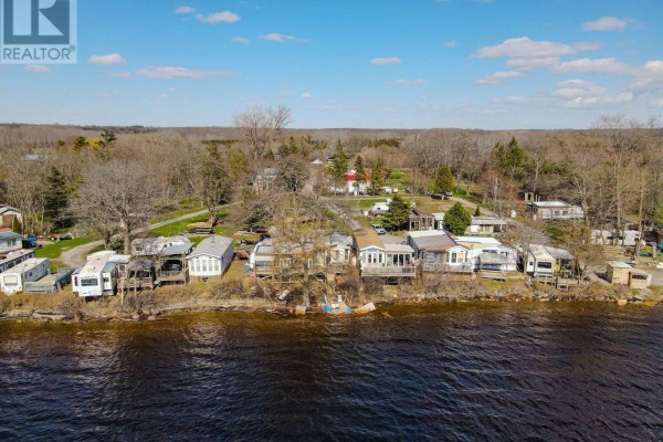 Expansive aerial view of a wide, calm river with wooded shores under a partly cloudy sky. - 181 Melville Road, Prince Edward County