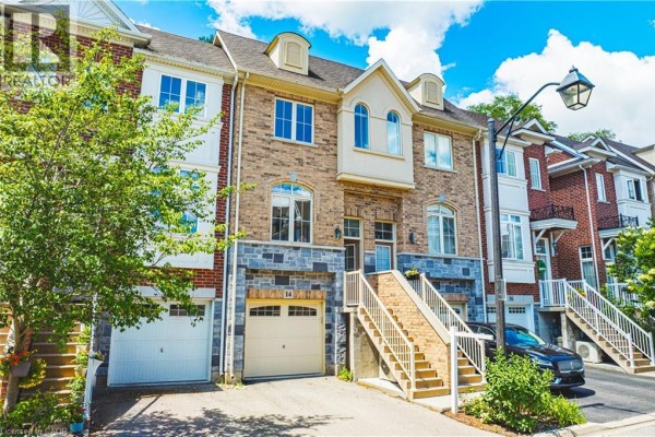 Close-up view of townhouse unit 14 with beige brick, stone accents, and garage. - 181 Plains Road W Unit# 14, Burlington