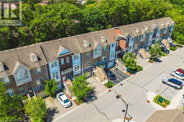 Aerial view of a townhouse complex with multiple units and a tree-lined background. - 181 Plains Road W Unit# 14, Burlington