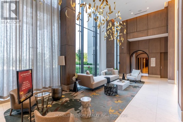 Lobby seating area with large windows, contemporary furniture, and decorative lighting. - 1810 - 30 Inn On The Park Drive, Toronto