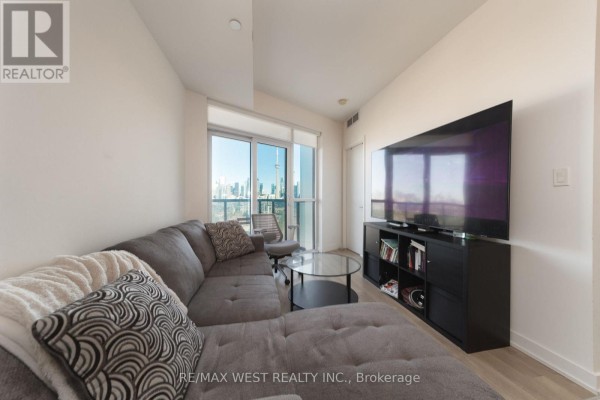 Living room with sectional sofa, TV, and large windows with city view. - 1810 - 50 Ordnance Street, Toronto
