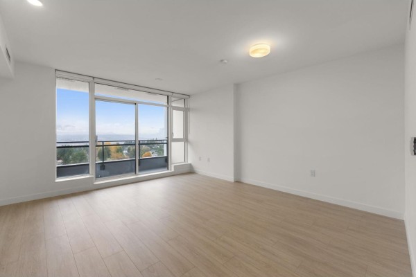 Empty living space with large window offering balcony access, light wood flooring, and neutral walls. - 1810 13675 107a Avenue, Surrey