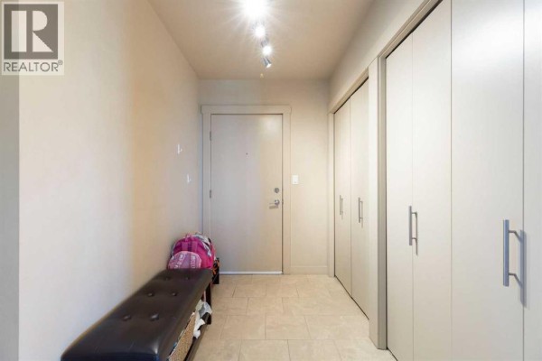 Hallway with tiled floor, beige walls, and large storage closets. - 1811, 8710 Horton Road Sw, Calgary