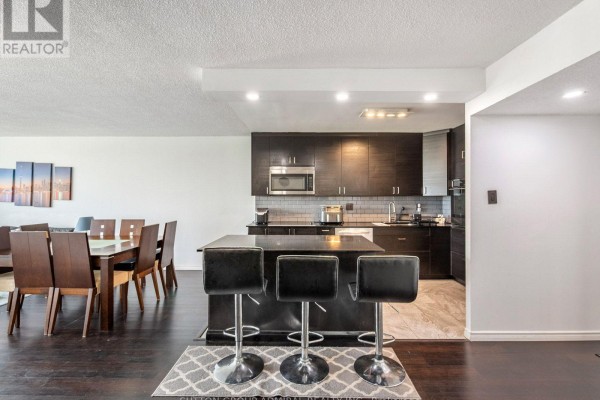 Dining area with wooden table, fruit centerpiece, and open layout to kitchen - 1811 - 10 Martha Eaton Way, Toronto