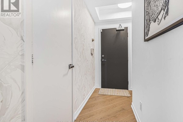 Apartment entryway with textured wallpaper, dark front door, and light wood floor. - 1811 - 21 Widmer Street, Toronto