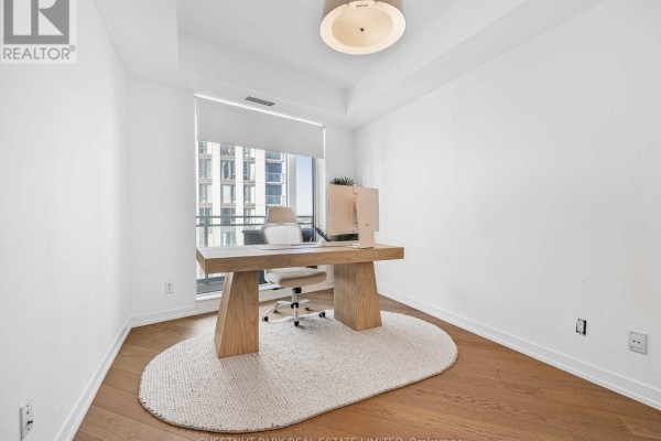 Home office with a wooden desk, ergonomic chair, and large window overlooking the city. - 1811 - 21 Widmer Street, Toronto