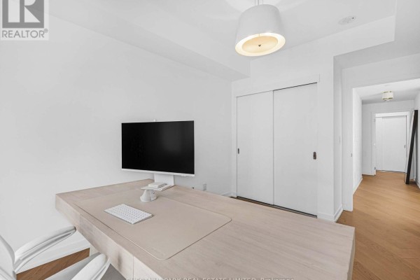 Office space with a long desk, computer, and sliding white closet doors. - 1811 - 21 Widmer Street, Toronto