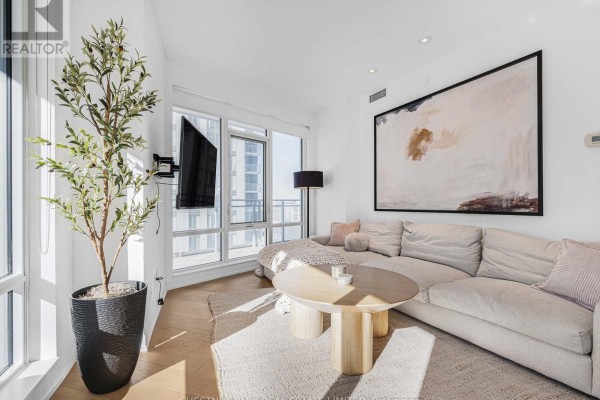 Living room featuring a sectional sofa, coffee table, artwork, and expansive windows. - 1811 - 21 Widmer Street, Toronto