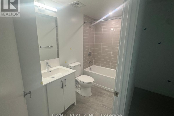 Bathroom with a white vanity, toilet, and bathtub with a tiled shower surround. Grey floor tiles. - 1811 - 4010 Eglinton Avenue W, Toronto