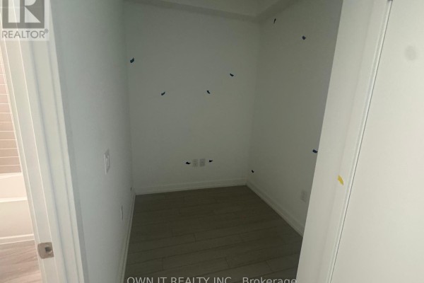Small room with grey wood-look floor tiles and white walls, adjacent to a bathroom. - 1811 - 4010 Eglinton Avenue W, Toronto