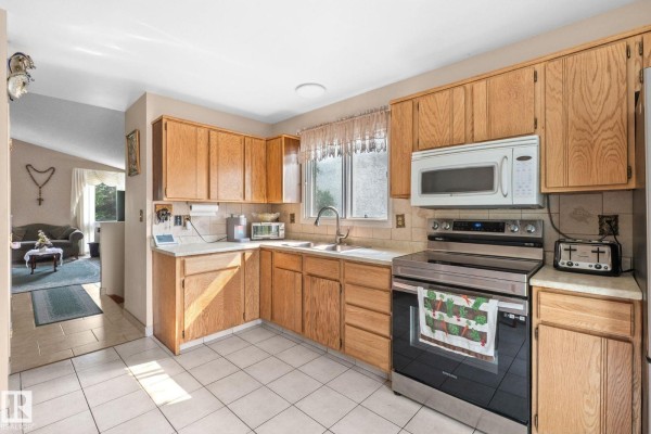 Kitchen with light oak wood cabinets, white countertops, stainless steel appliances, and tiled flooring. - 18126 98 Av Nw, Edmonton