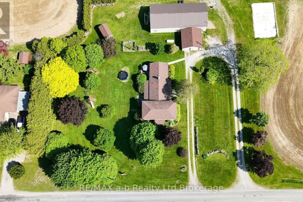 Overhead drone view of a farmhouse and outbuildings on a large green lawn. - 1813 Norfolk County 19 Road W, Norfolk