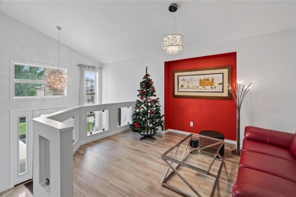 Living area with red sofa and view of kitchen island and staircase. - 1813 Templeton Avenue, Winnipeg