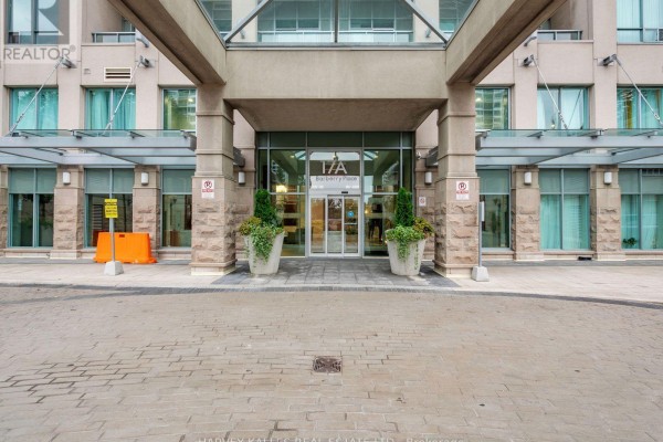 Front entrance of the condo building with stone pillars, glass doors, and potted plants. - 1814 - 17 Barberry Place, Toronto