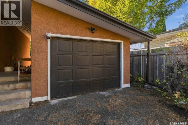 Exterior view of a dark brown garage door with textured stucco siding. - 1814 Wilson Crescent, Saskatoon