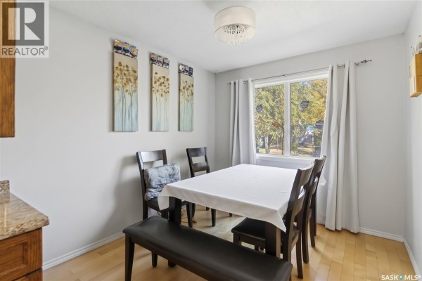 Dining room with a table set for four, dark wood chairs, and bench seating. - 1814 Wilson Crescent, Saskatoon