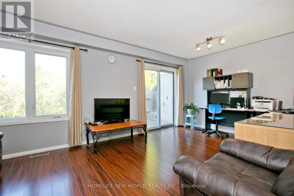 Living room features a sliding glass door to the outside, large window, desk, and entertainment center. - 1814 Woodgate Court, Oshawa