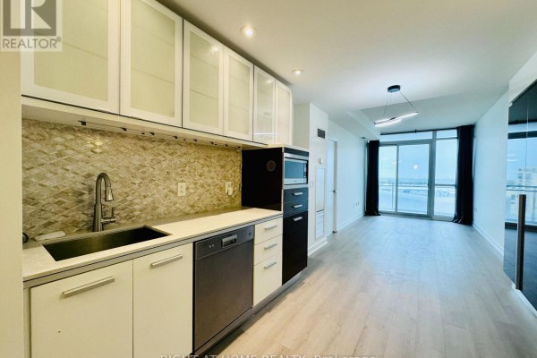 Kitchen with white cabinets, stainless steel appliances, and tiled backsplash. - 1815 - 38 Dan Leckie Way, Toronto