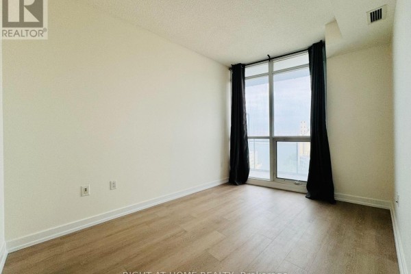 Bedroom with light wood floor, large window, and dark curtains. - 1815 - 38 Dan Leckie Way, Toronto