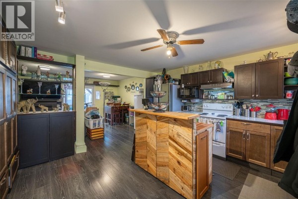 Covered patio with a hot tub, chairs, surfboards, and outdoor lighting. - 1816 43 Street, Vernon