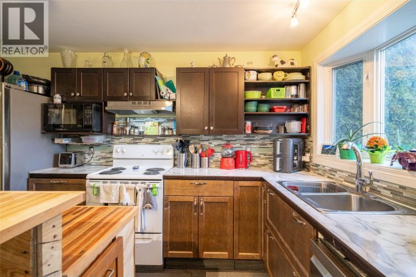 Dining area with a wooden table, chairs, a white refrigerator, and a glass door. - 1816 43 Street, Vernon