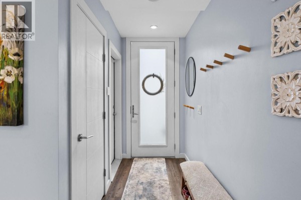Entryway with light blue walls, wood floor, and frosted glass front door. - 1818 Peak Point Court Unit# 30, West Kelowna
