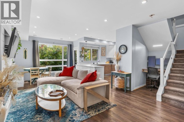 Living room with sectional sofa, coffee table, and kitchen with island. - 1818 Peak Point Court Unit# 30, West Kelowna