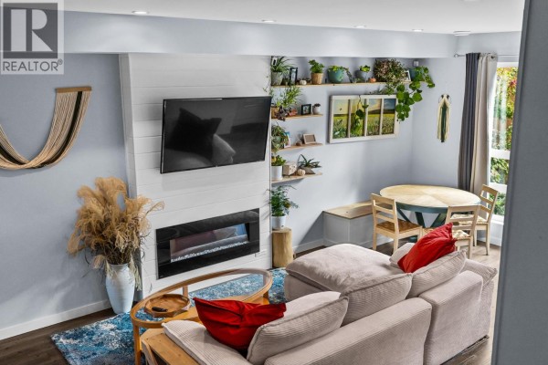 Living area with fireplace, TV, sectional sofa, and dining table. - 1818 Peak Point Court Unit# 30, West Kelowna