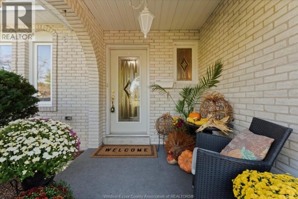 Close-up of the covered front entryway with a glass door, welcome mat, and fall decorations. - 182 Centennial, Tecumseh