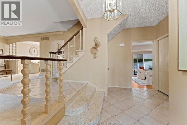 Interior foyer with a curved staircase, beige walls, tiled floor, and access to other rooms. - 182 Centennial, Tecumseh