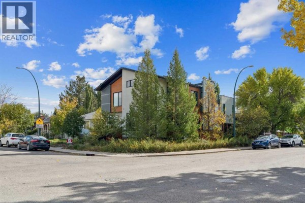 Street view of the duplex at 1820 4 Street Ne, Calgary, with trees and parked cars. - 1820 4 Street Ne, Calgary