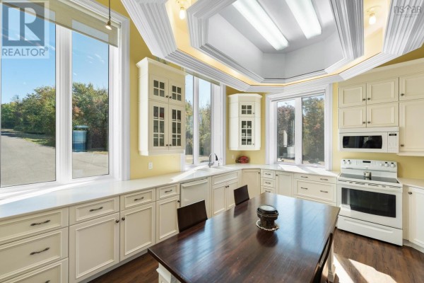 Kitchen island with a wooden table and chairs, surrounded by cream cabinets and white appliances. - 1820 Culloden Road, Culloden