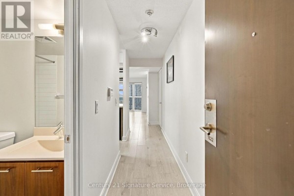 View from inside an apartment entrance, showing a hallway with white walls and wooden floors. - 1822 - 135 Village Green Square, Toronto