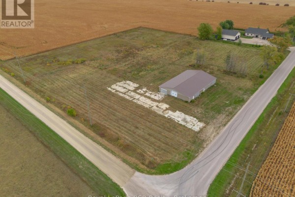 Aerial view of a commercial building on a large property surrounded by fields, with houses and a road nearby. - 1822 Concession 12 Concession, Huron Kinloss