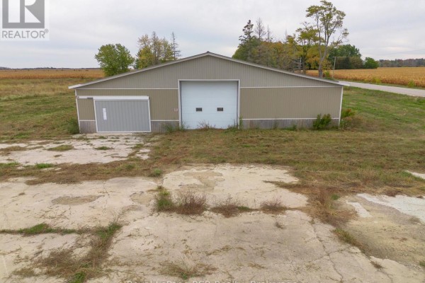Front view of a commercial building with a large white garage door and a smaller grey roll-up door on a concrete pad. - 1822 Concession 12 Concession, Huron Kinloss