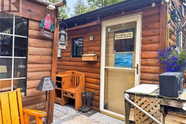 Close-up of the wooden cabin entrance with a chair, bench, and boots by the door. - 18246 Highway 540, Evansville
