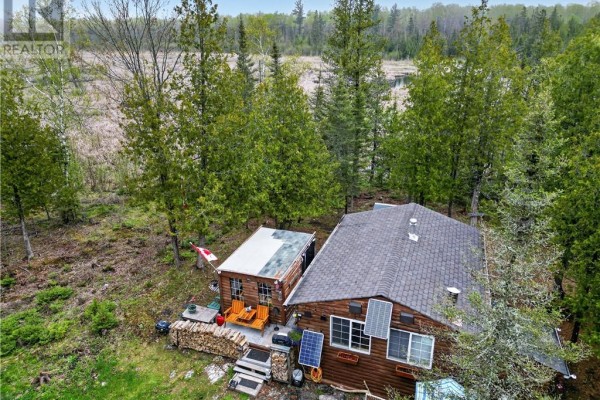 Aerial view of the wooden cabin and adjacent structure surrounded by trees and water. - 18246 Highway 540, Evansville