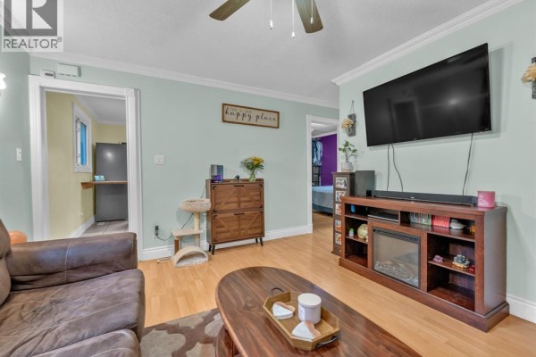 Living room with light green walls, a sofa, entertainment unit, and doorways to other rooms. - 1826 Francois Road, Windsor