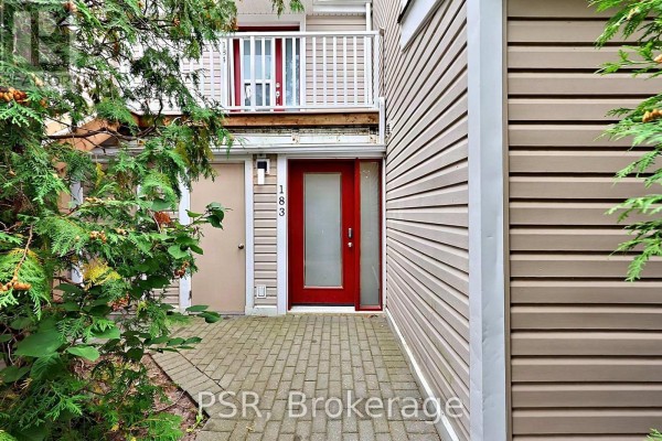 Close-up of the front door and exterior details, surrounded by evergreen trees. - 183 - 49 Trott Boulevard, Collingwood