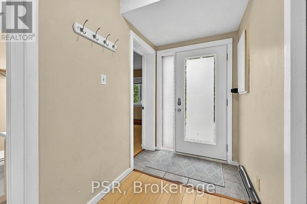 Entrance hallway with light beige walls, a coat rack, and a double glass door. - 183 - 49 Trott Boulevard, Collingwood