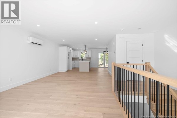 Rear view of the duplex showing grey siding, patio doors, and nearby undeveloped land. - 183 Carrington Drive, Riverview