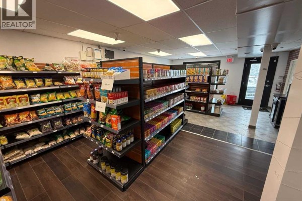Store interior with wood slat walls displaying packaged goods, glass display cases, and a checkout counter. - 183 Pembina Avenue, Hinton