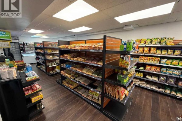 Retail store showing packaged food items on wood slat walls, a checkout counter, and refrigeration units. - 183 Pembina Avenue, Hinton
