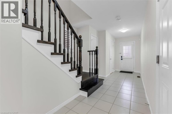 Hallway featuring staircase, tiled floor, and access to living area. - 183 Penny Lane, Stoney Creek