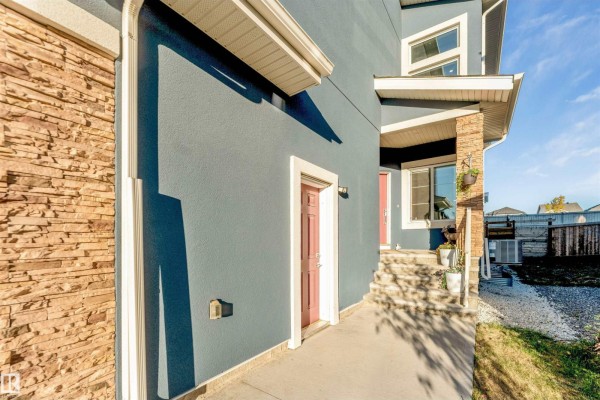 Side entrance of the house with stone pillar details and a red door. - 1831 18 St Nw, Edmonton