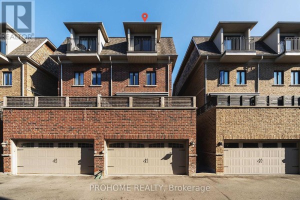Rear exterior of townhouses showing garages, brickwork, and balconies. - 1831 Pagehurst Avenue, Mississauga