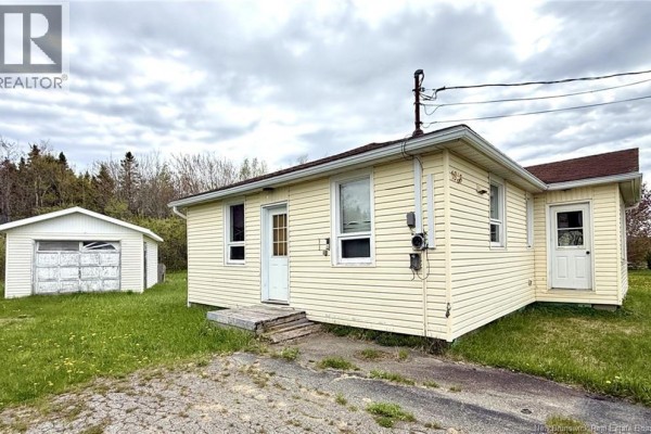 Side exterior view of the pale yellow bungalow showing two entrances and a detached garage. - 1833 Route 335, Saint Simon