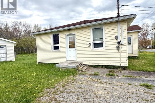 Front right exterior view of the pale yellow bungalow with a concrete driveway and grass. - 1833 Route 335, Saint Simon