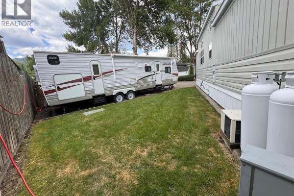 Wide view of backyard with lawn, deck, and surrounding trees - 1835 Bakery Frontage Road Unit# 125 & 126, Christina Lake
